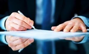 Business man hand signing on document at desk